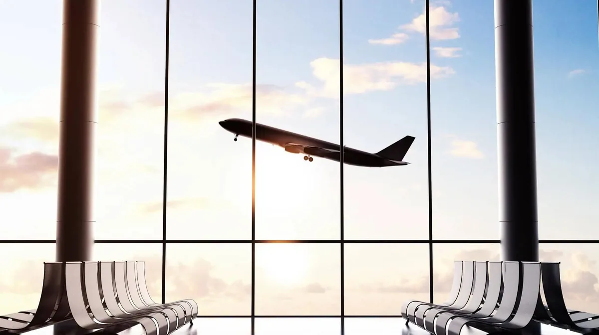 Avião comercial decolando, visto do saguão de embarque através do vidro