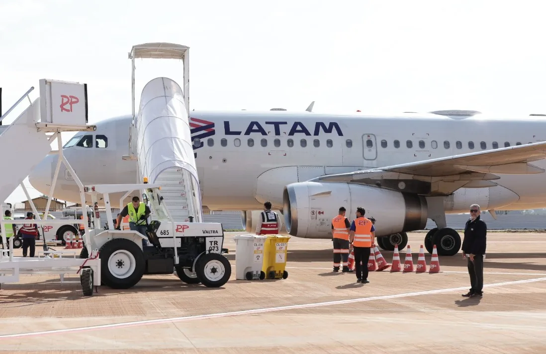 Airbus da Latam no pátio do Aeroporto de Dourados, com escada de embarque acoplada e equipe de solo em serviço