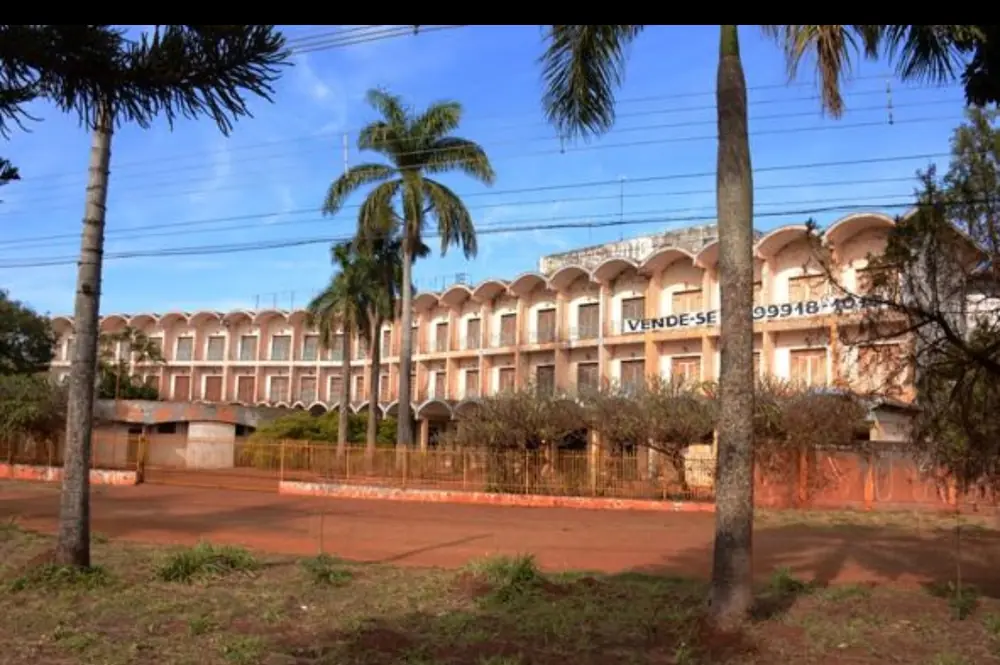 Fachada do Dourados Park Hotel com faixa de vende-se pendurada e terreno de terra em frente