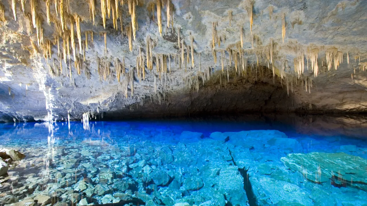 Lago de água azul intensa no interior da Gruta do Lago Azul, sob estalactites