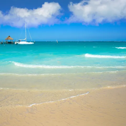 Mar turquesa do Caribe com um barco ao longe e faixa de areia clara