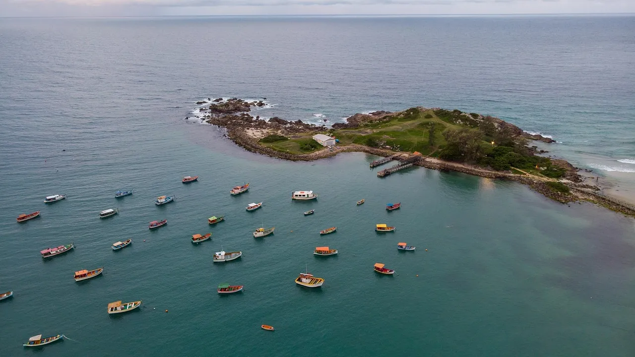 Ilha com vegetação e barcos ancorados em mar calmo