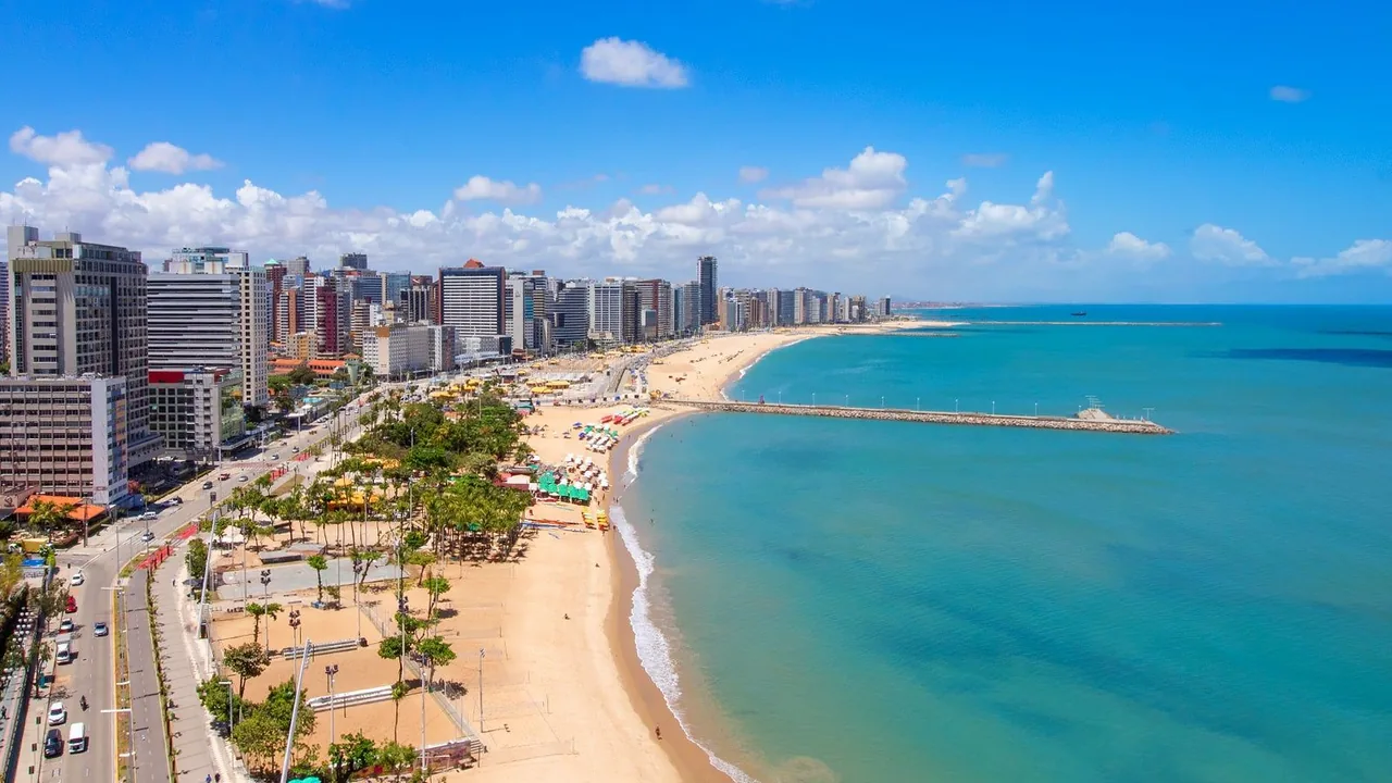 Orla de Fortaleza com prédios à beira-mar e a faixa de areia curva