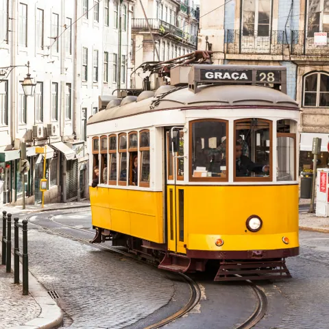 Bonde amarelo subindo rua estreita de Lisboa