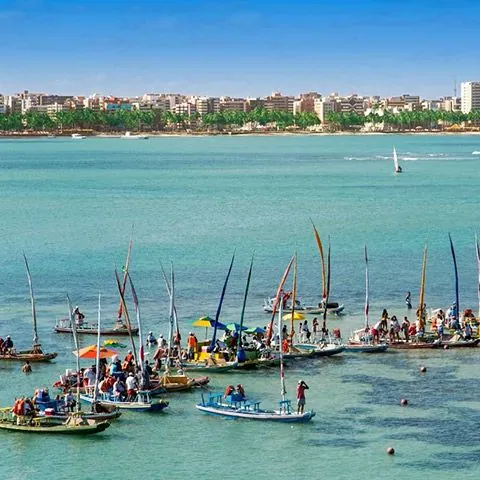 Jangadas ancoradas em mar verde claro, na orla de Maceió