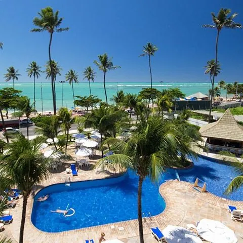 Piscina de resort à beira-mar cercada de coqueiros
