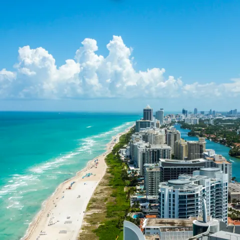 Prédios altos de Miami à beira da praia, com o mar em primeiro plano