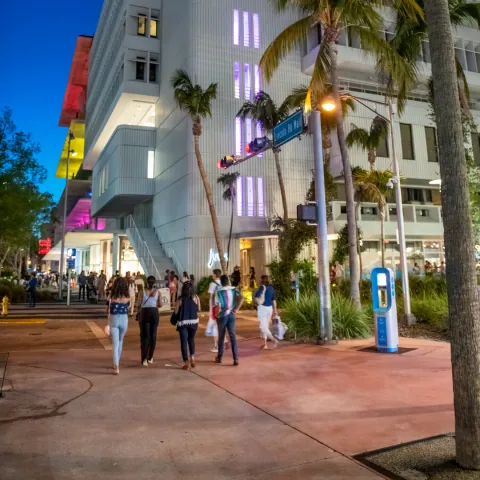Rua de Miami com pessoas caminhando entre prédios claros