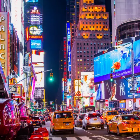 Times Square à noite, com os painéis luminosos e o movimento de pessoas