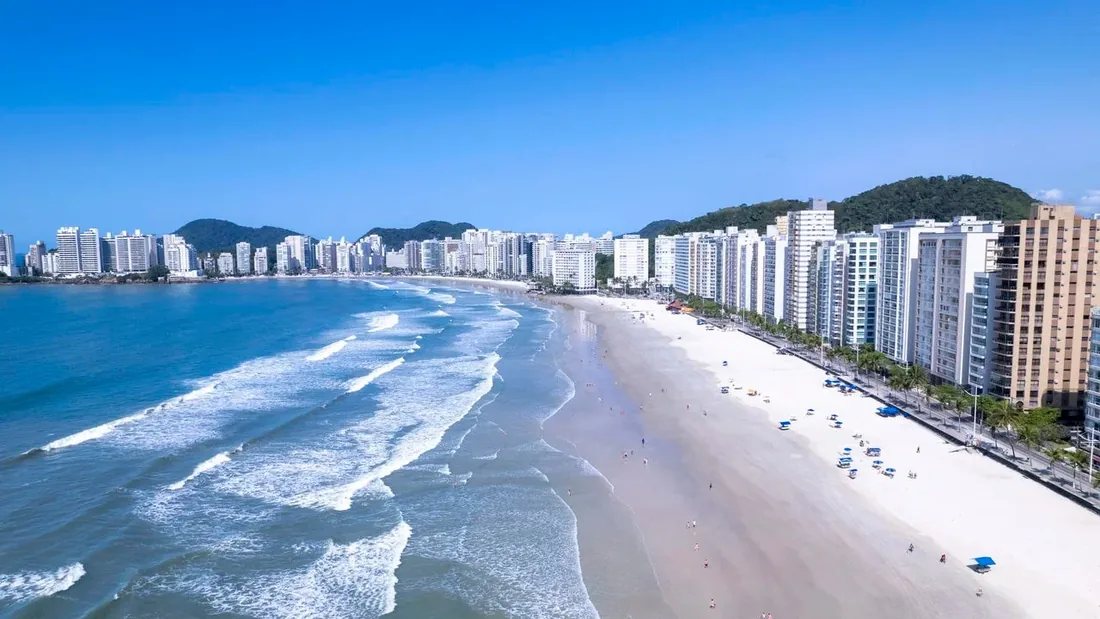 Orla urbana do Guarujá, no litoral de São Paulo, com prédios à beira da praia