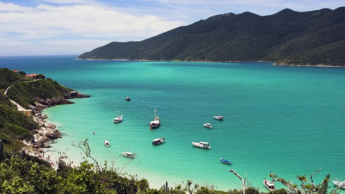 Praia de Arraial do Cabo, no litoral do Rio de Janeiro, com água transparente e morros ao fundo