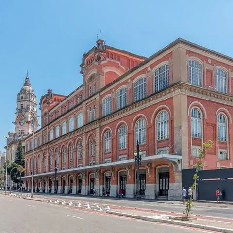 Prédio histórico de tijolos aparentes com torre de relógio ao fundo, no centro de São Paulo